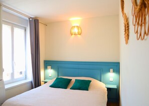 Relax in a spacious room with a large bed, two bedside tables, and a wall-mounted light fixture.