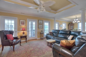 A living room with a leather sofa, armchairs, a patterned rug, and a ceiling fan.
