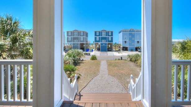Udsigt fra en veranda til et bygningskompleks under en klar himmel.