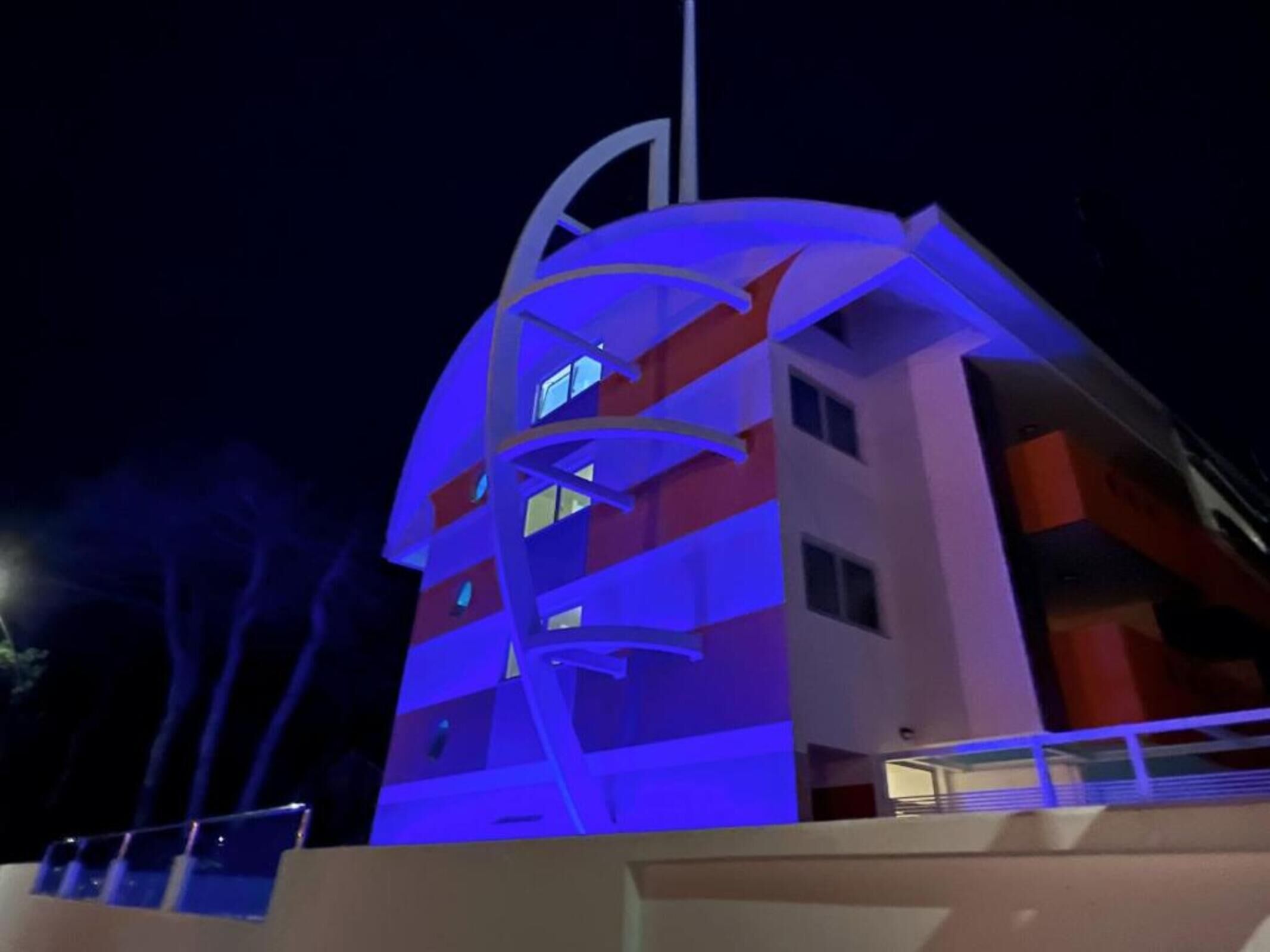 A multi-story building with balconies and a flagpole.