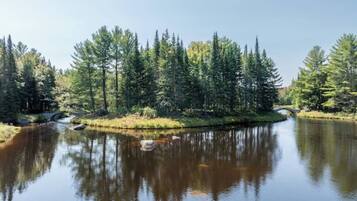 A calm lake surrounded by dense forest and a small bridge.