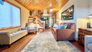 A cozy living room with a wooden ceiling, a sofa, a chair, a rug, and a staircase leading to another room. - Townhouse with the amazing views!  Garage, 3 bedroom, Hot Tub! (Mount Crested Butte)