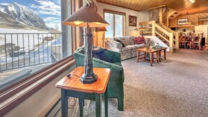 A cozy living room with a view of a snowy mountain, a wooden ceiling, and a dining area with a staircase. - Townhouse with the amazing views!  Garage, 3 bedroom, Hot Tub! (Mount Crested Butte)