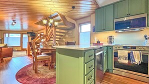 A spacious kitchen with wooden floors, a green island with drawers, a built-in oven, and a large window. - Townhouse with the amazing views!  Garage, 3 bedroom, Hot Tub! (Mount Crested Butte)