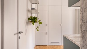 Une salle de bain moderne avec des meubles blancs, un comptoir en marbre et une plante en pot.