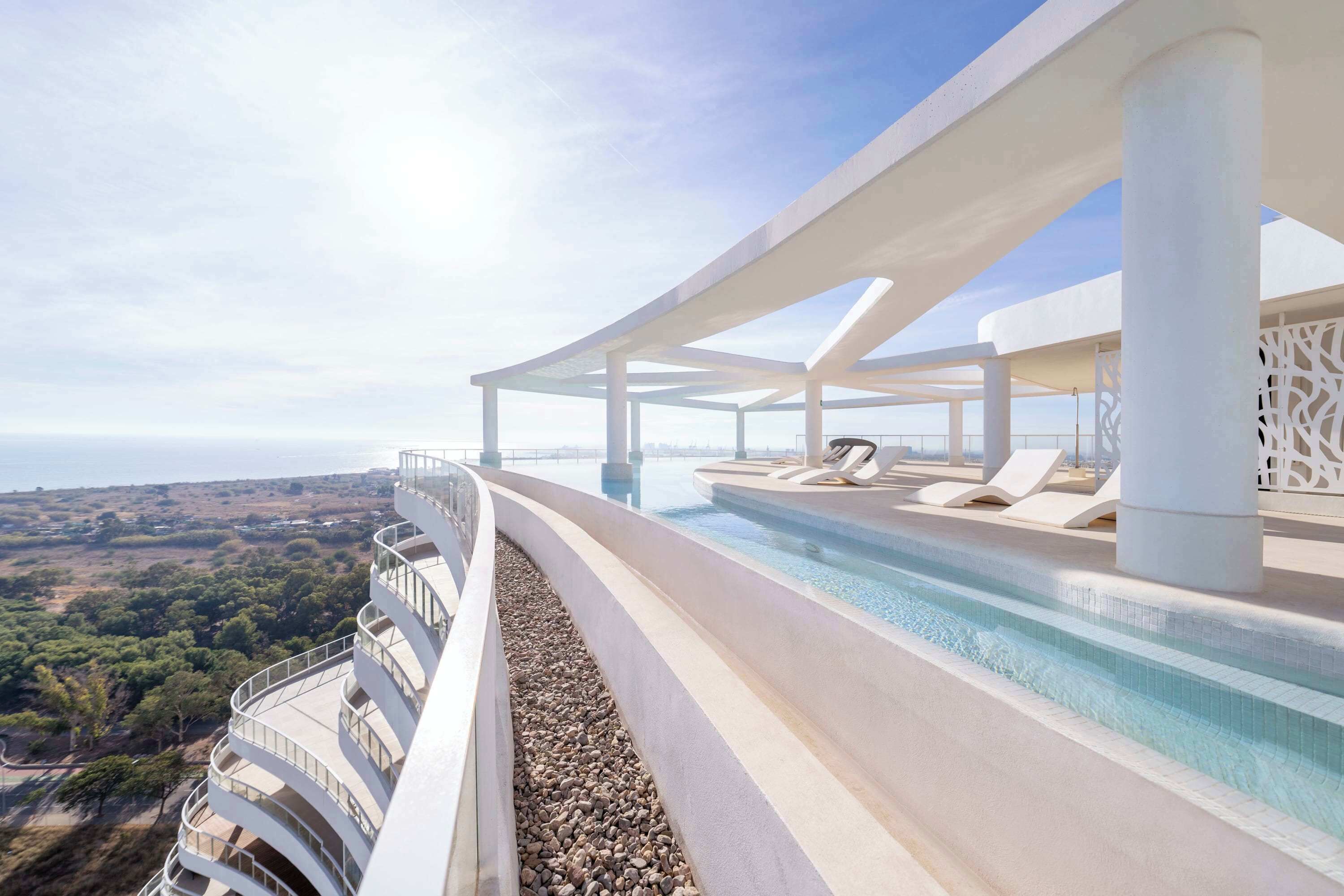 Um hotel moderno com piscina, área externa para sentar e vista para a paisagem.