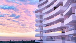 Un immeuble à plusieurs étages doté de balcons, probablement un hôtel ou un ensemble d’appartements, offrant une vue sur la mer.