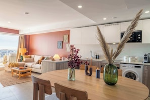 A modern living room with a dining area, kitchen, and a large window with a view.