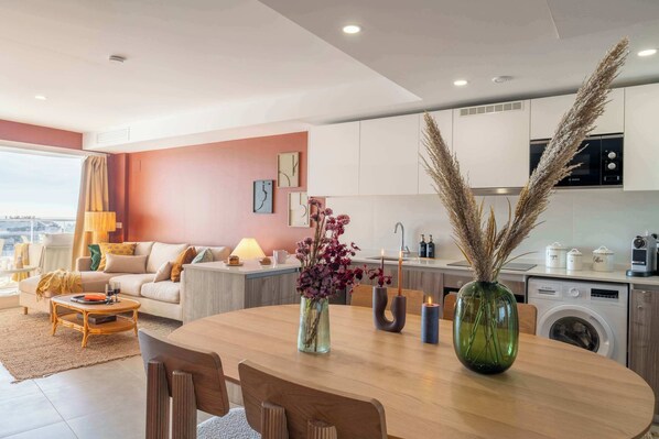 Una sala de estar moderna con comedor, cocina y un ventanal con vistas.