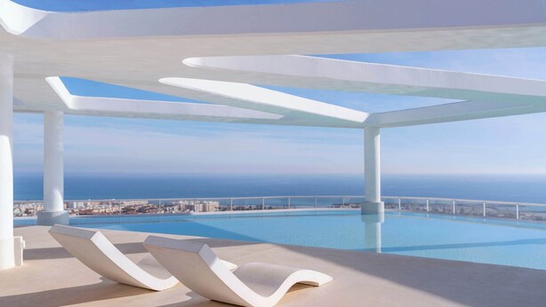 Un espace de détente extérieur moderne, doté d’une piscine, de chaises longues blanches et offrant une vue sur l’océan.