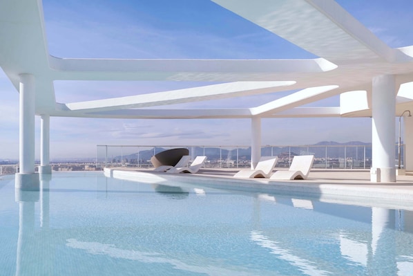 An indoor infinity pool with white lounge chairs and a modern architectural design.