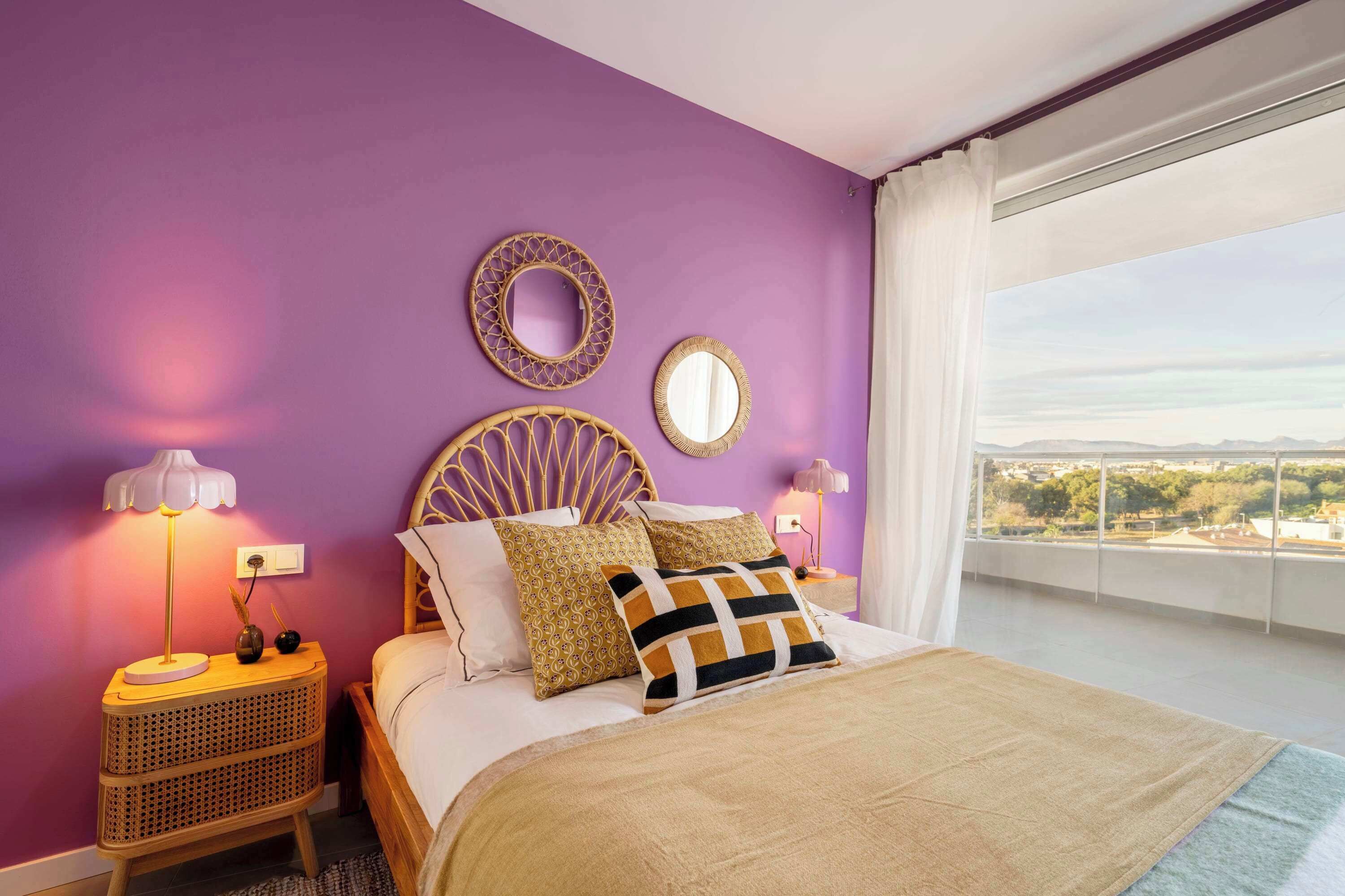 Ein Schlafzimmer mit einem Bett, zwei Nachttischen, einem Fenster mit Aussicht und zwei Wandspiegeln.