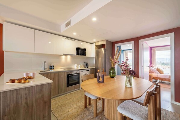 A modern kitchen with white cabinets, a wooden island, and a dining area with a wooden table and chairs.