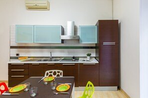 Una cocina moderna con una mesa de comedor preparada para dos personas, un horno empotrado y un refrigerador.