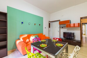 Una sala moderna con sofá, mesa de comedor, sillas y televisor.
