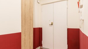 A hallway with a red and white color scheme, a door with a golden handle, and a red mat with white text at the entrance. - Central Station Apts by Wonderful Italy - Cetara (Napoli)