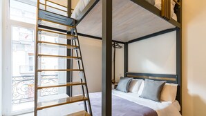 A room with a bunk bed, a ladder, a window with a view of buildings, and a bed with pillows. - Central Station Apts by Wonderful Italy - Capri (Napoli)