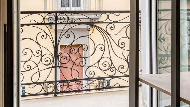 A view from a balcony with ornate metal railings and a window with a wooden blind. - Central Station Apts by Wonderful Italy - Capri (Napoli)