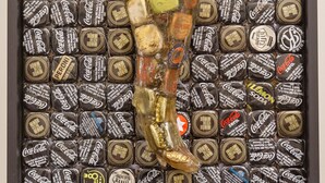 Ein gerahmtes Arrangement von Coca-Cola Artikeln, darunter Flaschen und Dosen, angeordnet in einem Gittermuster.