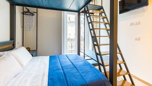 Un dormitorio con una cama, una escalera, un televisor y un balcón.