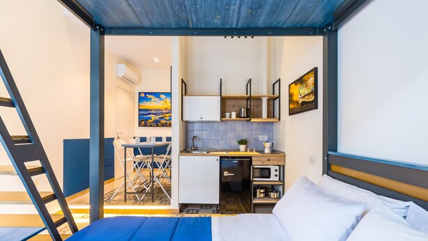 Una habitación pequeña con una cama, una kitchenette y un comedor.