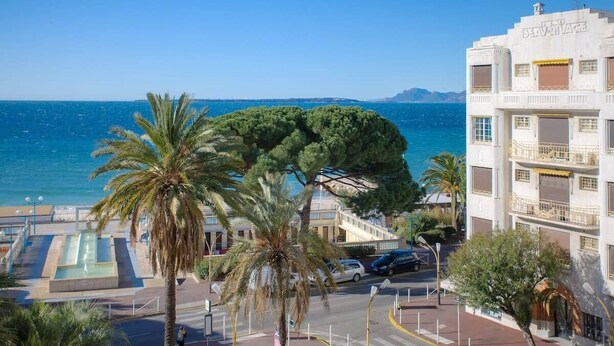 A coastal building with a pool, palm trees, and a view of the sea. - Studio with seafront terrace (Antibes)
