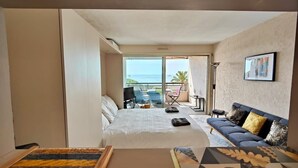 A hotel room with a bed, a sofa, a dining table, and a balcony with a view of the sea. - Studio with seafront terrace (Antibes)