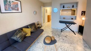 A living room with a dark sofa, a round coffee table, and a dining area with a table and chairs. - Studio with seafront terrace (Antibes)
