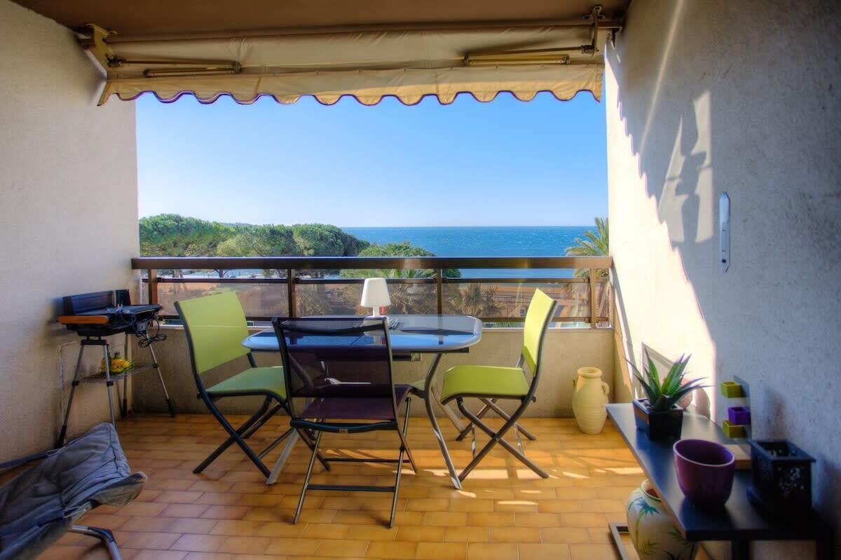 A balcony with a table and chairs, a laptop, and a potted plant.