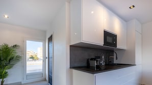 Una cocina moderna con armarios blancos, encimera negra y microondas integrado.