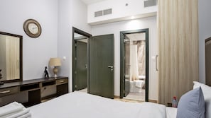 Ein Hotelzimmer mit Bett, Schreibtisch mit Lampe, Spiegel, Kleiderschrank und einem durchgegangenen Tür angedeuteten Badezimmer.