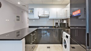A compact kitchen with a built-in washer and dryer, a microwave, and a refrigerator. - Luxury StayCation - Elegant 1BR Apartment in the Heart of Dubai (Dubai)