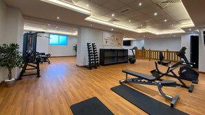 A gym with exercise equipment, wooden flooring, and a motivational quote on the wall. - Luxury StayCation - Elegant 1BR Apartment in the Heart of Dubai (Dubai)