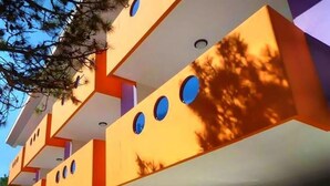 A modern building with a unique architectural design featuring multiple levels and circular windows. - Comfort and Relax by the Pool-beahost (San Michele al Tagliamento)