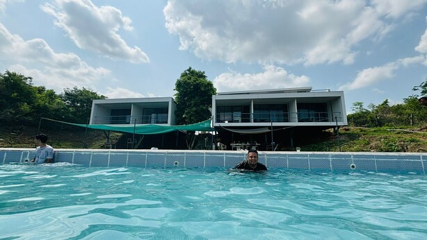 Una piscina con dos edificios modernos al fondo.
