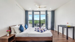 Un dormitorio con cama, mesita de noche, mesa y vistas al exterior.