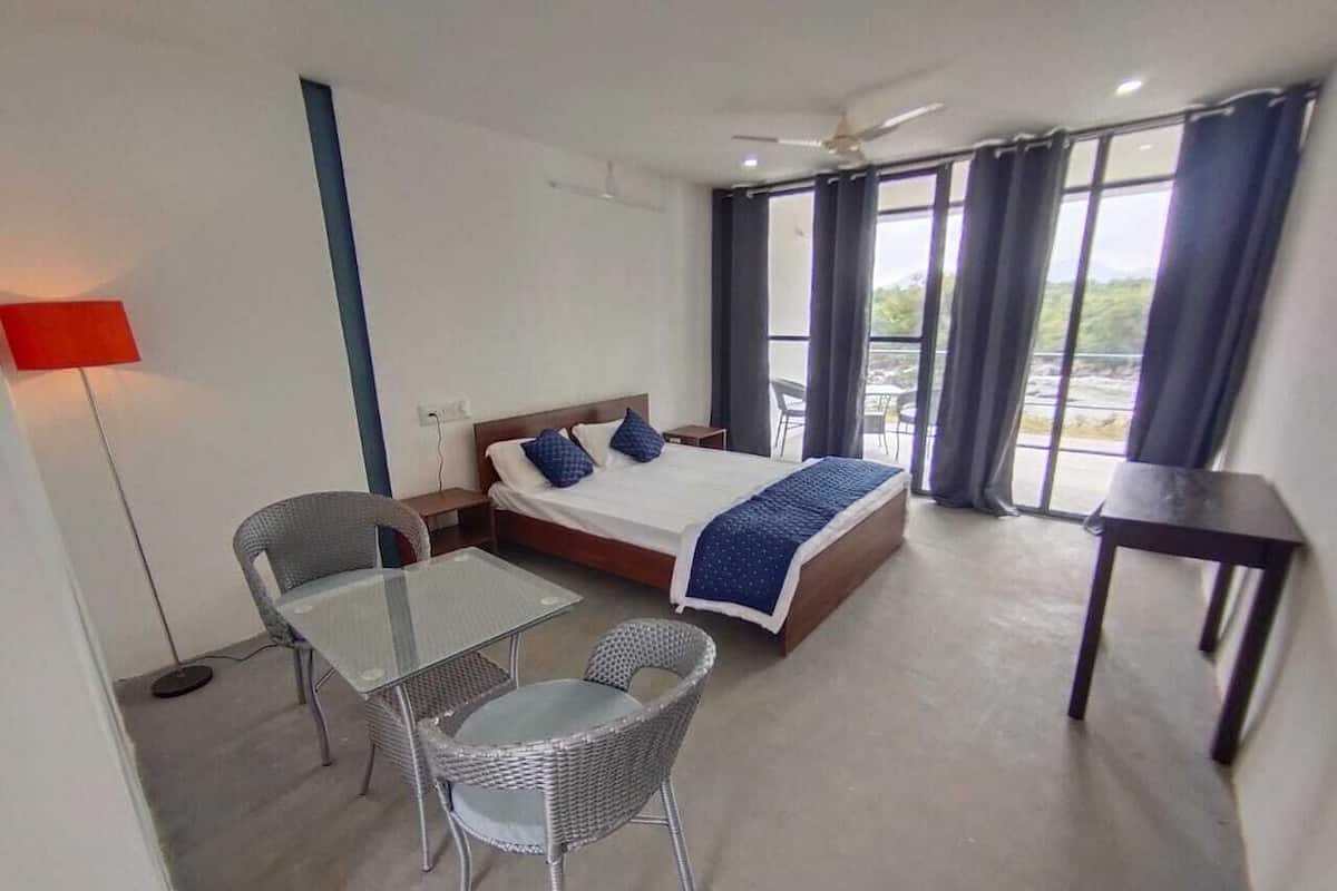Habitación de hotel con cama, dos sillas, una mesa, un escritorio y vistas al exterior.