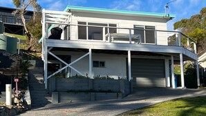 A two-story house with a garage, a balcony, and a staircase leading to the upper floor. - PIPI SHACK Iconic waterfront shack at Binalong Bay Beach, Bay of Fires (Binalong Bay)