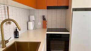 A modern kitchen with a stainless steel sink, a built-in oven, and a dishwasher. - PIPI SHACK Iconic waterfront shack at Binalong Bay Beach, Bay of Fires (Binalong Bay)