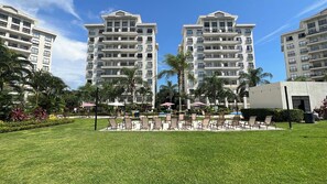 A hotel with multiple floors, outdoor seating, and palm trees.