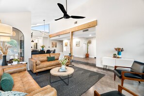 A spacious living area with a leather sofa, a round coffee table, and a ceiling fan.