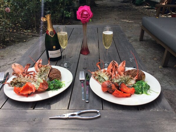 Dos platos de langosta sobre una mesa de madera con una botella de Bollinger champagne y copas de vino.