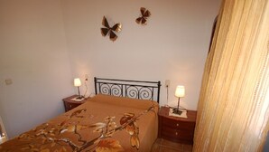 A bedroom with a bed, two bedside tables, a wall-mounted lamp, and a decorative butterfly on the wall. - SAONA VILLAS (VN ANGEL): villa for 4 people, private pool, wifi, near the sea (L'Ametlla de Mar)