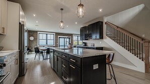 A modern kitchen with a central island, dark cabinetry, and pendant lighting. - Panoramic mountain view/Hot Tub/Shuffleboard/Theater room  Sunday River (Newry)