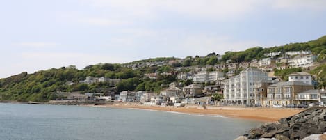 A coastal town with a beach, rocky shoreline, and hillside buildings.