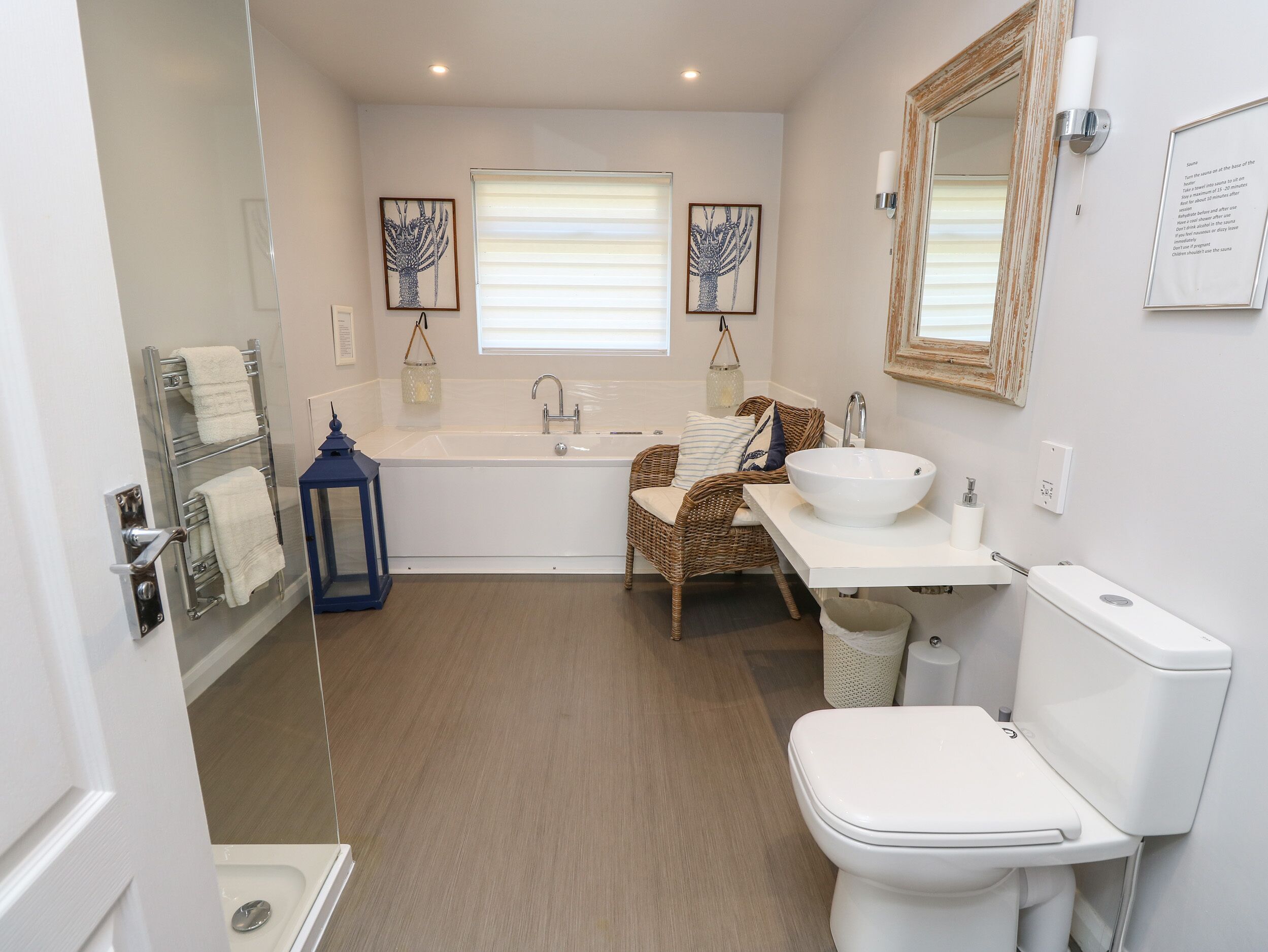 Et moderne badeværelse med badekar, vask, toilet og en fletstol.