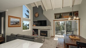A spacious living area with a fireplace, a large window, and a dining table. - Carnelian Woods # 126 by Hauserman Rental Group (Carnelian Bay)