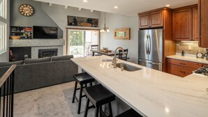 A modern kitchen with a large island, built-in appliances, and a cozy seating area with a fireplace. - Carnelian Woods # 126 by Hauserman Rental Group (Carnelian Bay)