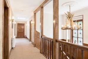 A hallway with wooden paneling, a radiator, a chandelier, and a door at the end. - Daweswood, Patterdale luxurious, spacious home with walks from the door (Patterdale)