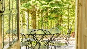 A dining area with a round table and chairs, surrounded by a forest. - Daweswood, Patterdale luxurious, spacious home with walks from the door (Patterdale)